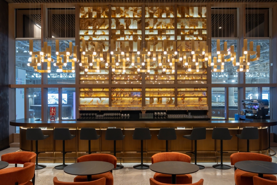 Vue intérieure du salon Latam à l'aéroport international de Jorge Chávez, avec un bar élégant avec un éclairage moderne, des sièges et une palette de couleurs chaude.